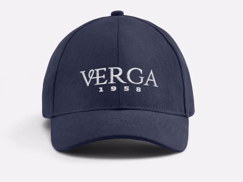Un cappellino dadhat di colore blue navy con una visiera curva. Sulla parte frontale è ricamato il logo "VERGA 1958" in bianco. Il design del cappellino è semplice e classico, con cuciture visibili che ne delineano la struttura. Il materiale è resistente e adatto a proteggere dal sole, rendendolo ideale per un uso quotidiano.